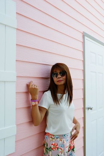 Woman wearing sunglasses standing by house