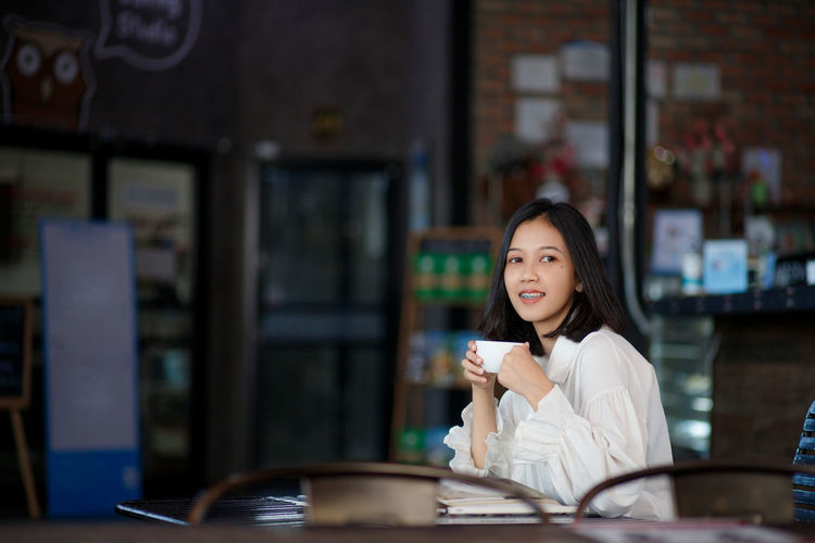 Portrait of young woman using mobile phone in cafe