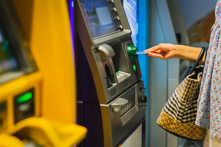 Woman hand insert a credit card into an atm machine