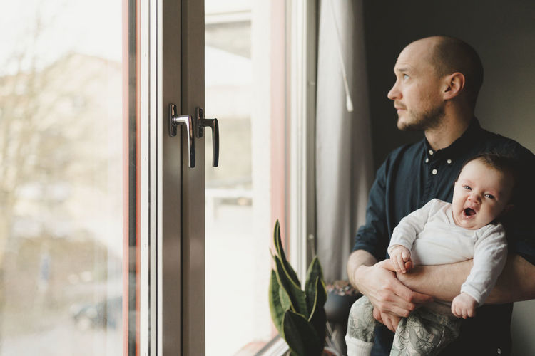 Father with baby looking through window