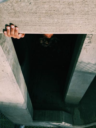 Upside down image of man standing behind concrete wall