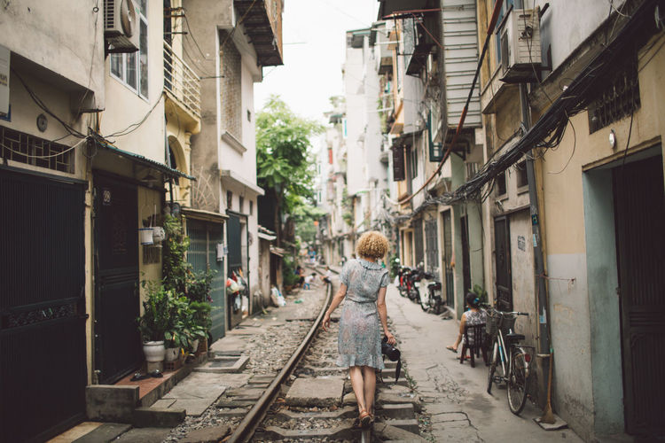 Woman walking on railroad track in city