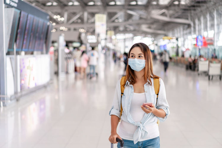 Woman wearing mask using mask standing at airport