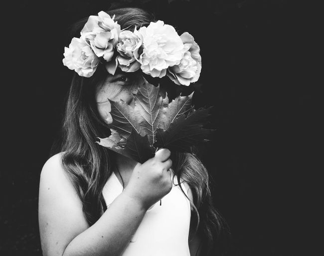 Portrait of girl wearing floral garland holding leaves