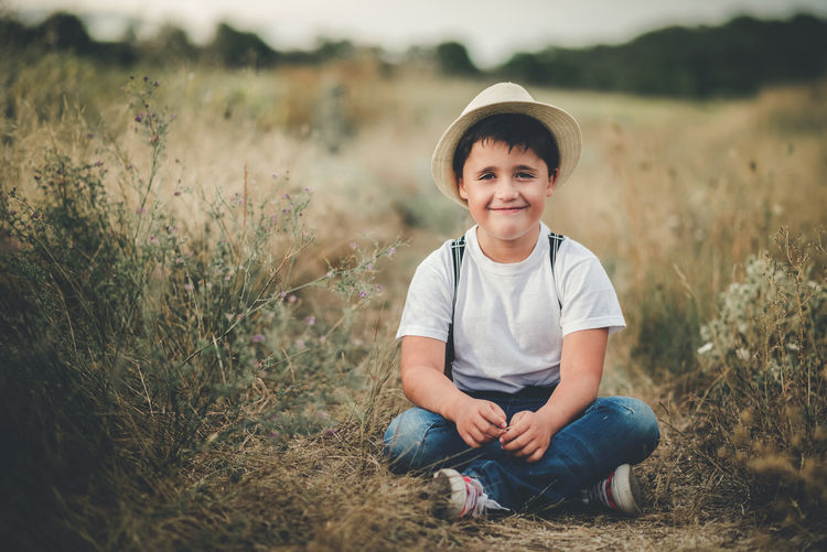 Portrait of smiling boy sitting on land