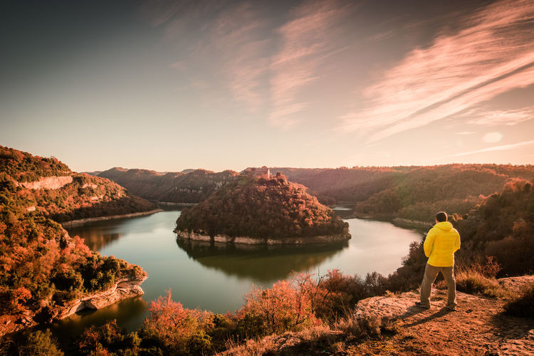 View of man standing by horseshoe bend in ter river and mountain with sant pere de casserres abbey
