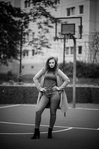 Portrait of young woman standing at basketball court