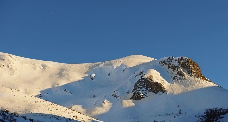 Scenic view of snowcapped mountains against clear blue sky