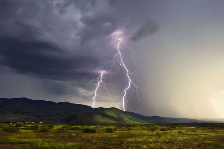 Lightning over landscape against storm clouds