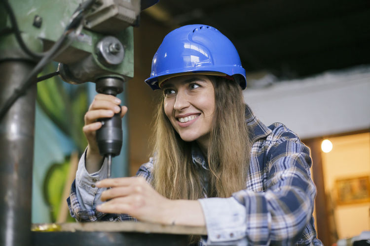 Close-up of woman using drill in workshop