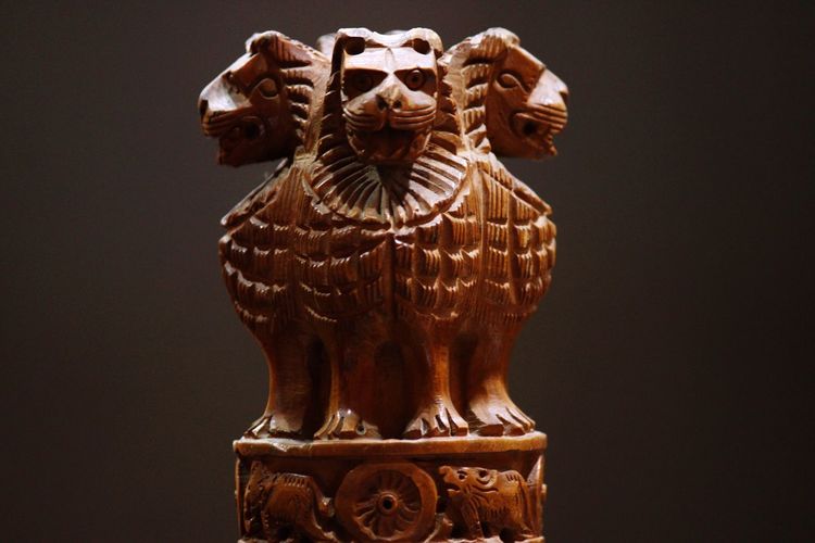 Close-up of wooden national emblem statue against gray background