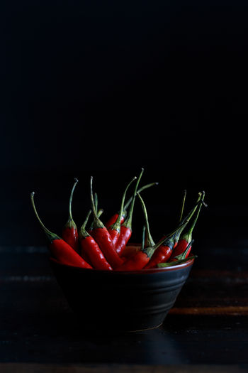 Red hot chili peppers bowl on wooden table and black background..