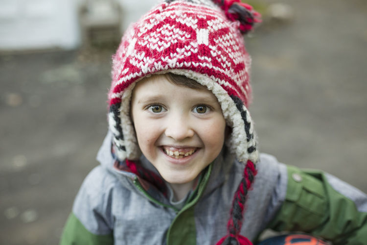 Close-up portrait of happy boy wearing warm clothing standing in backyard