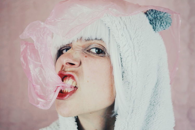 Close-up of woman in costume with pink plastic against wall