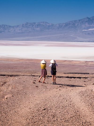 Rear view of friends standing in desert against mountains