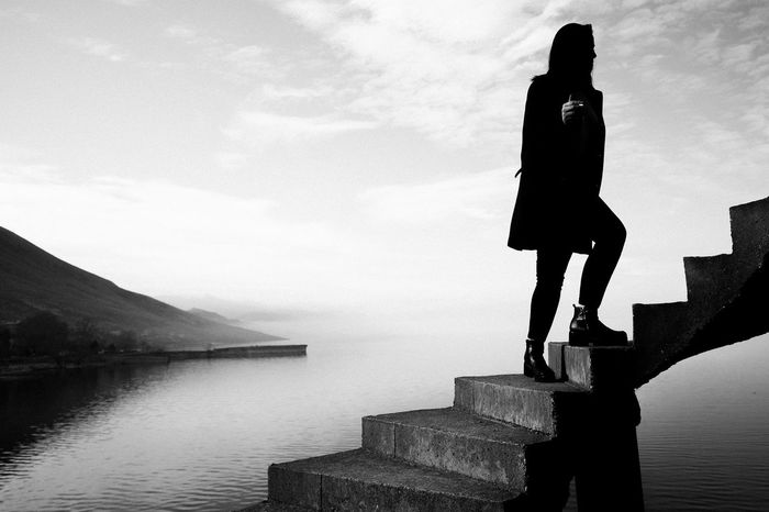 Silhouette of woman standing on steps against lake