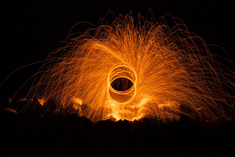 Low angle view of steel wool display against sky at night