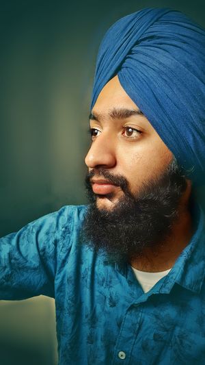 Portrait of young sikh man against blue background