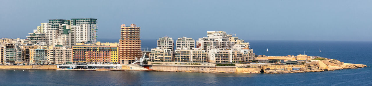 City at waterfront against clear sky