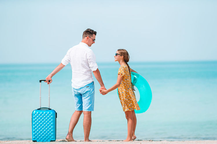Full length of father and daughter standing on beach
