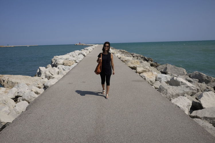 Full length of woman walking on pier against clear sky