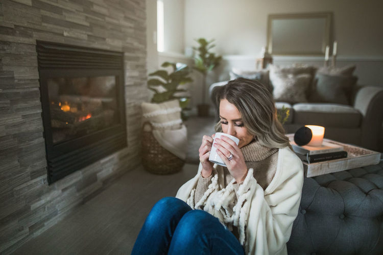 Young woman drinking coffee while sitting at home