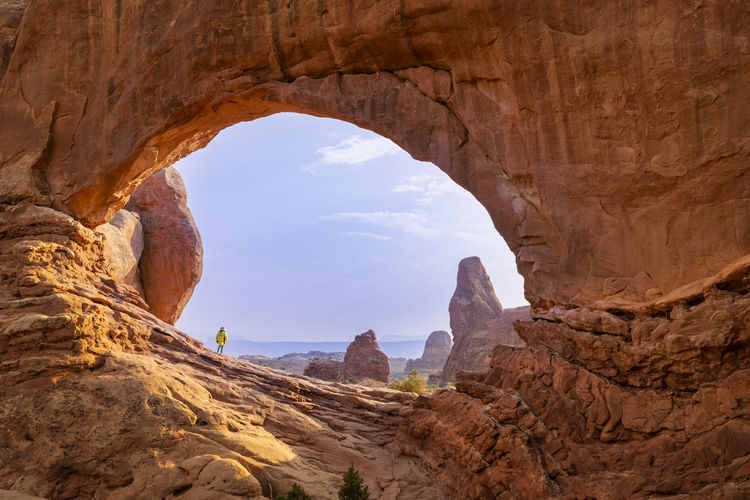 Female hiker framed in the north window against blue sky in arches
