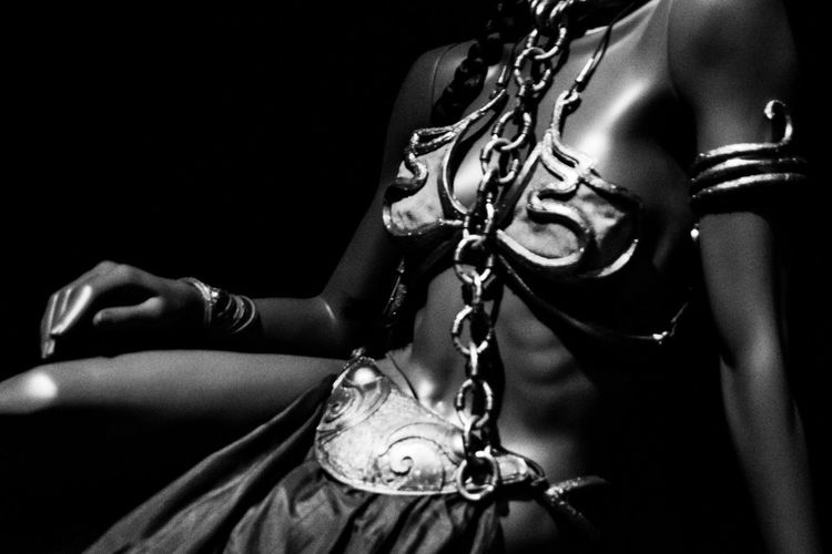 Midsection of woman holding mask against black background
