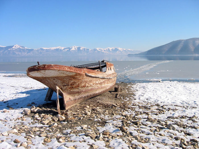 Abandoned boat moored on beach against sky