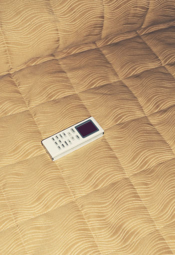 High angle view of air conditioner remote on bed at home