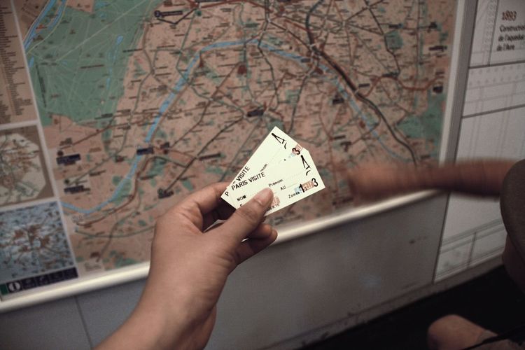 Cropped image of person holding train ticket against map at station