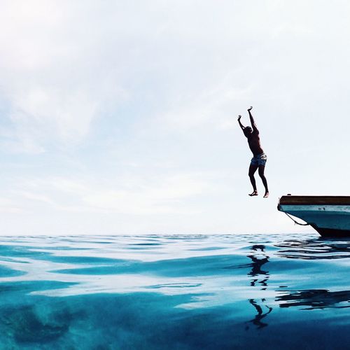 Man jumping in sea against sky