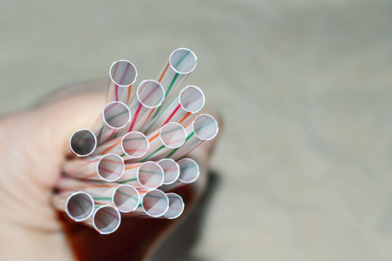 Cropped hand of person holding drinking straws
