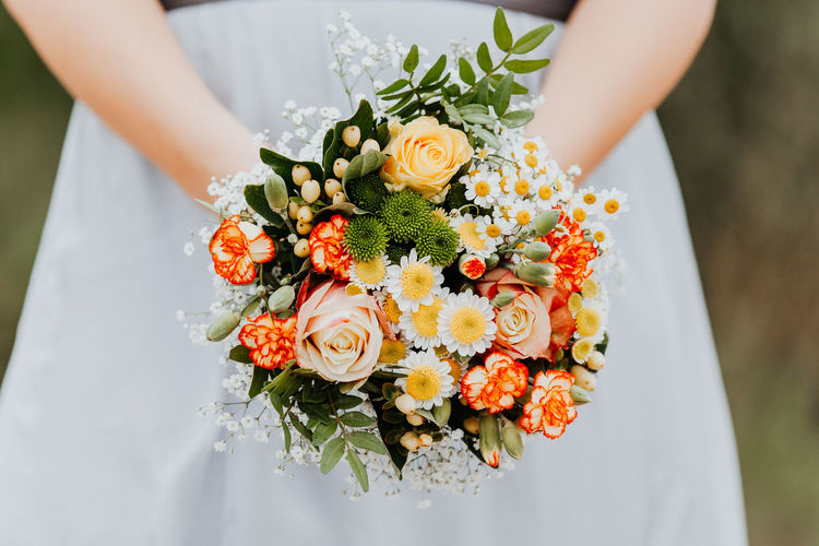 Close-up of hand holding bouquet of red rose flower