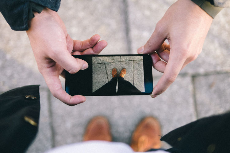 Cropped hands of man photographing person legs 