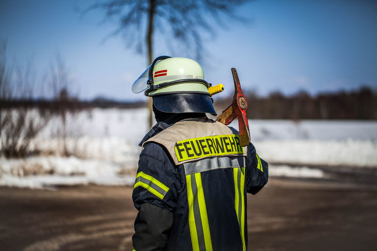 Rear view of firefighter holding work tool