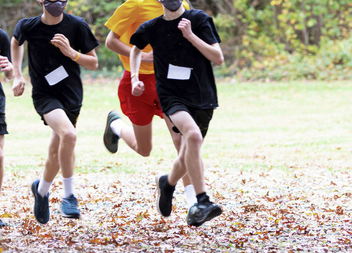 Low section of men running in public park during pandemic