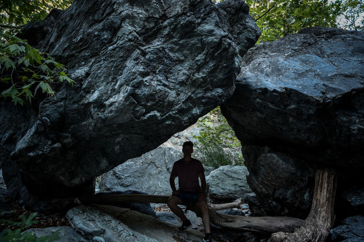 Full length of man sitting by rock