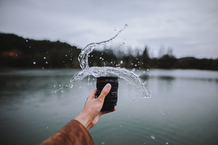 Man holding water splashing on lake