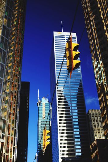 Low angle view of traffic light against modern buildings in city