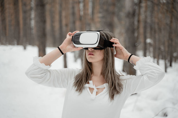 Woman wearing virtual reality simulator against trees outdoors