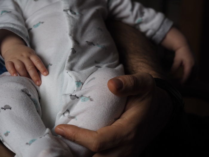 Cropped hand of parent holding baby at home