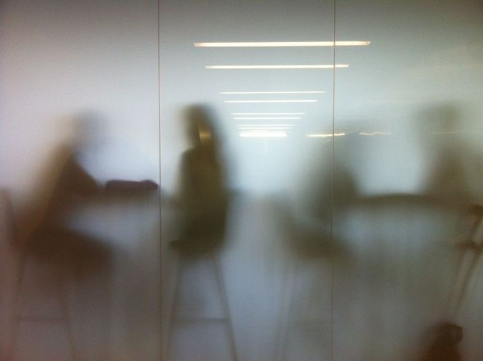 People sitting on chairs in cafe seen through glass