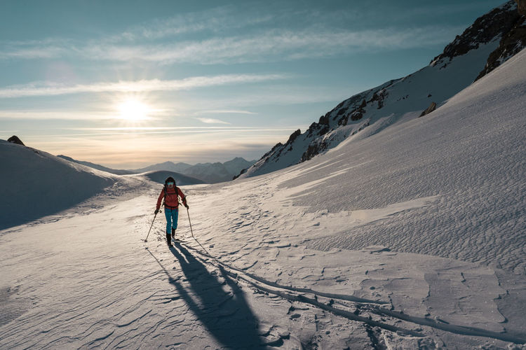 Woman skiing on snowcapped mountain against sky