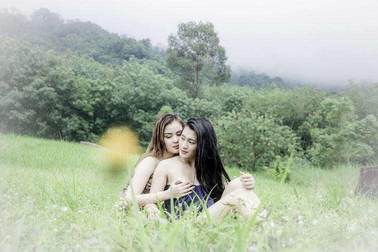Portrait of two women sitting on grassy field