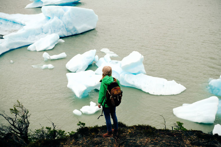 High angle view of woman standing overlooking icebergs at lago grey