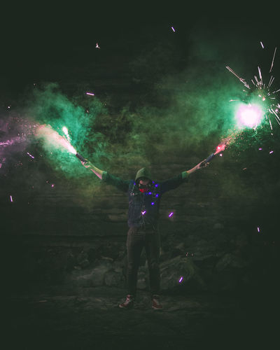 Man holding lit sparklers at night