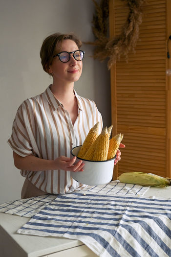 Young woman holding food while sitting on table