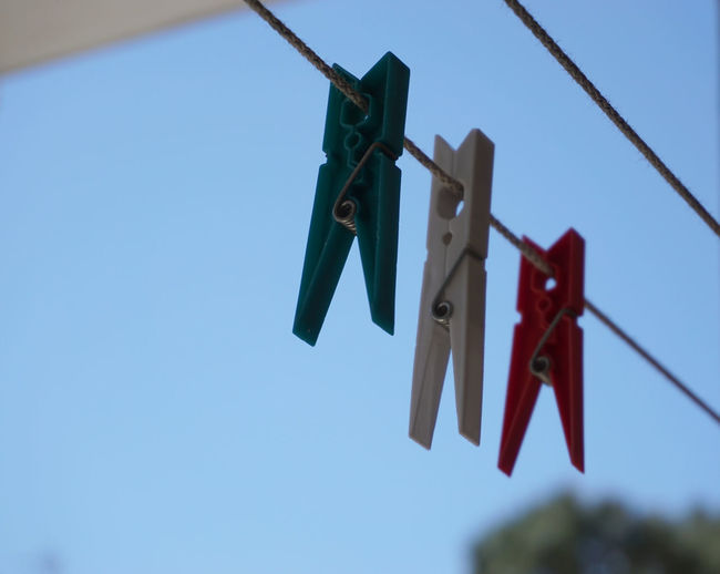 Low angle view of clothespins hanging on clothesline against sky