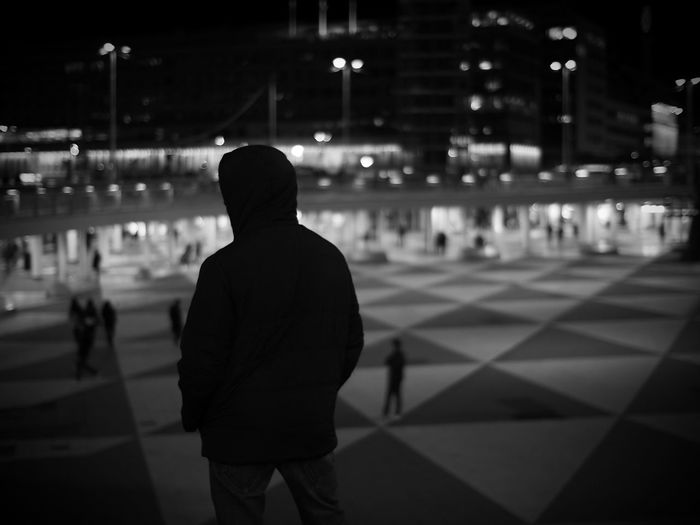 Rear view of man standing in city at night